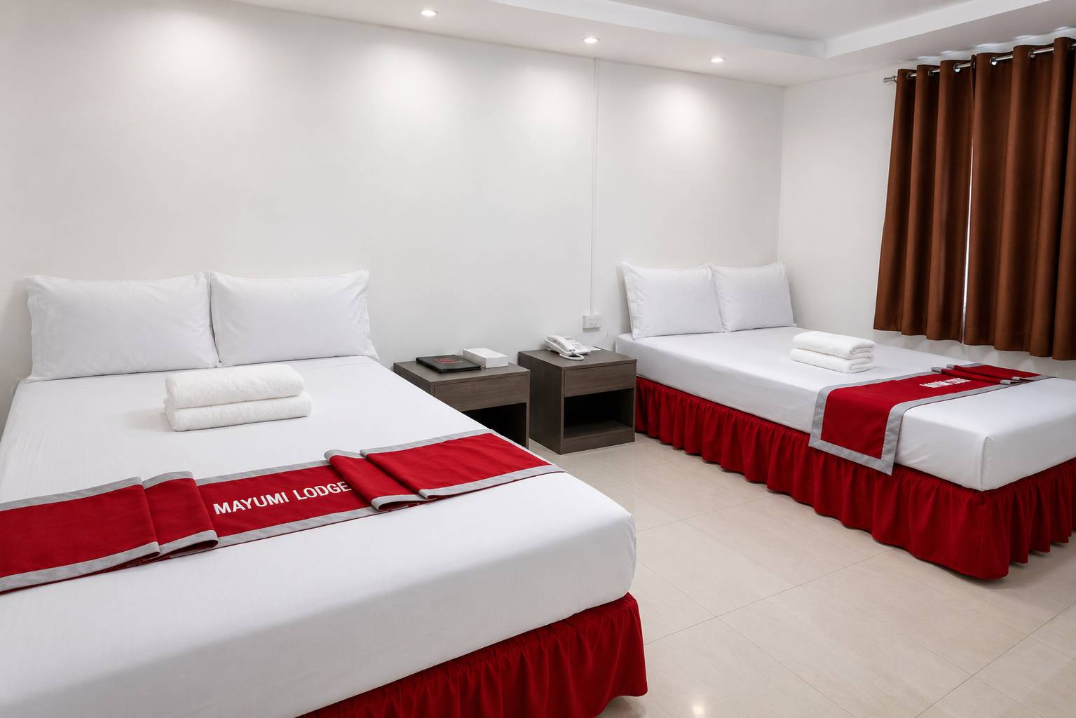 Two beds made up with white linen and red Mayumi Lodge bed runners in a bright studio room